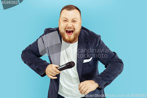 Image of Young man with microphone on blue background, leading concept