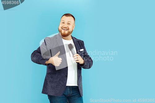 Image of Young man with microphone on blue background, leading concept