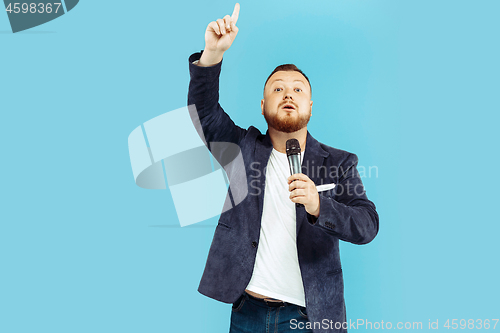 Image of Young man with microphone on blue background, leading concept