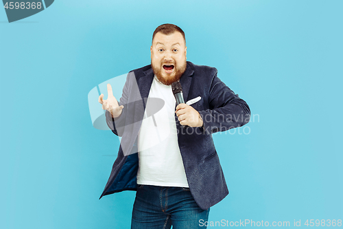 Image of Young man with microphone on blue background, leading concept