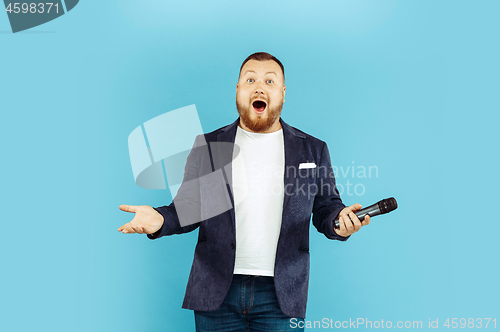 Image of Young man with microphone on blue background, leading concept