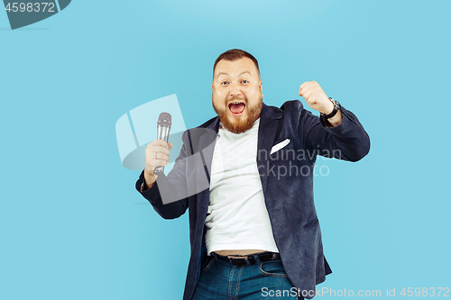 Image of Young man with microphone on blue background, leading concept