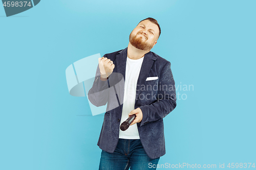 Image of Young man with microphone on blue background, leading concept