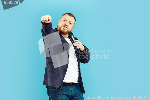 Image of Young man with microphone on blue background, leading concept