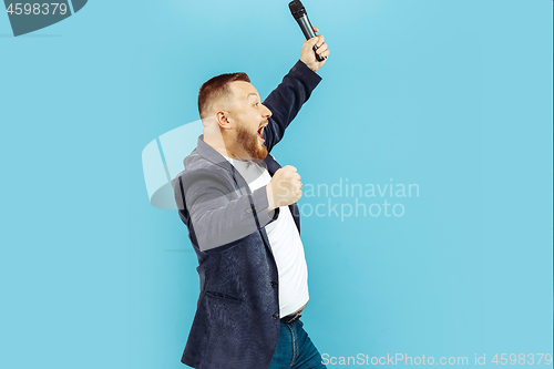 Image of Young man with microphone on blue background, leading concept