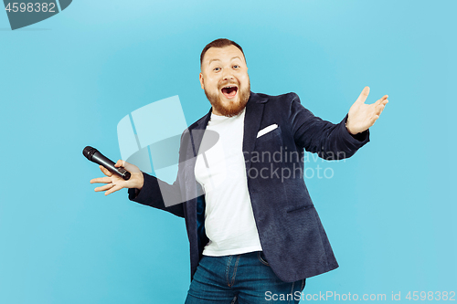 Image of Young man with microphone on blue background, leading concept