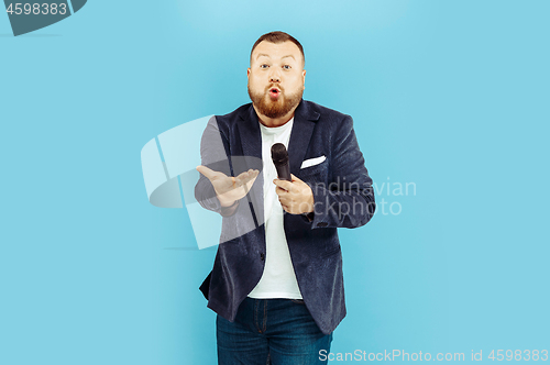 Image of Young man with microphone on blue background, leading concept