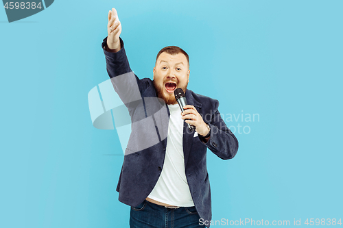 Image of Young man with microphone on blue background, leading concept