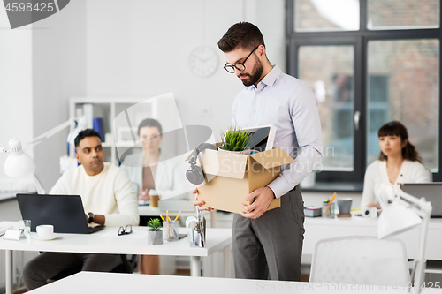 Image of sad fired male office worker with personal stuff