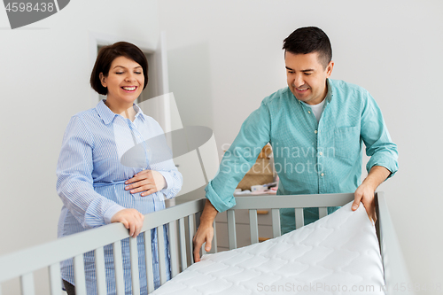 Image of family couple arranging baby bed with mattress