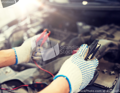 Image of auto mechanic man with cleats charging battery