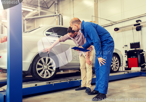 Image of auto mechanic with clipboard and man at car shop