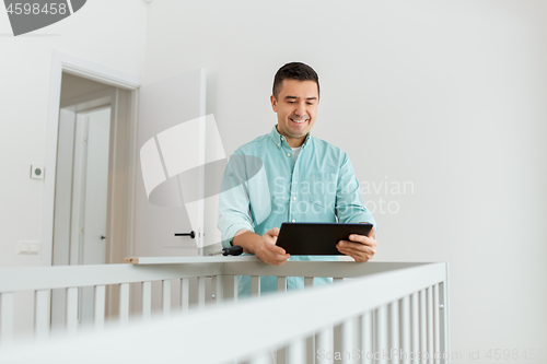 Image of father with tablet pc assembling baby bed at home