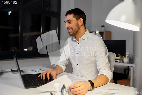 Image of businessman with laptop working at night office