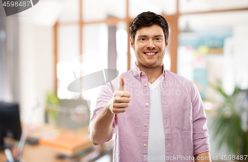 Image of happy young man showing thumbs up over office room