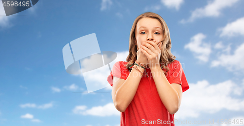 Image of shocked teenage girl covering her mouth over sky
