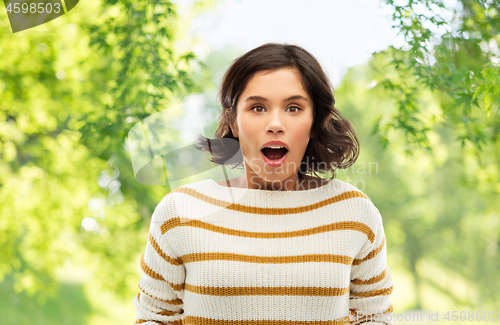 Image of surprised young woman over natural background