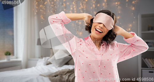 Image of happy young woman in pajama and eye sleeping mask