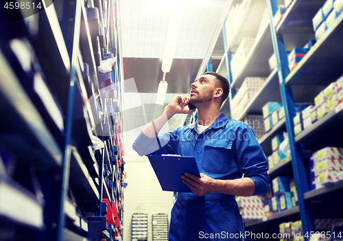 Image of auto mechanic calling on smartphone at car shop