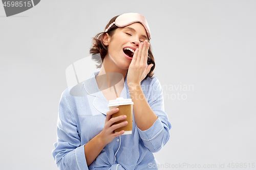 Image of woman in pajama and eye mask with coffee yawning