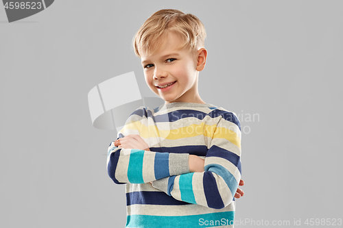 Image of smiling boy in striped pullover with crossed arms