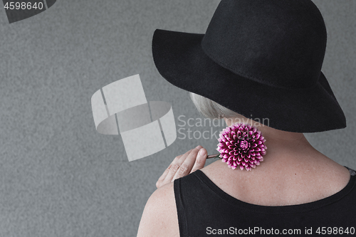 Image of Lady with black hat holding red dahlia