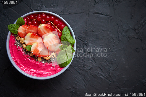 Image of Summer berry smoothie or yogurt bowl with strawberries, red currants and chia seeds on black