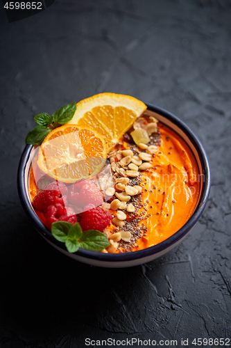 Image of Bowl with fresh healthy smoothie or yogurt. With orange slices, tangerine, raspberry, chia and nuts