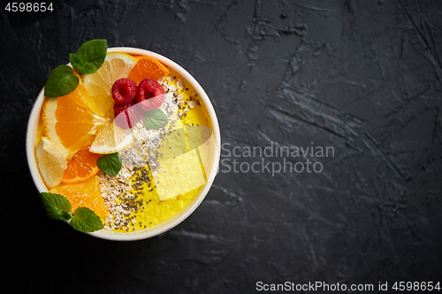 Image of Tasty orange fresh smoothie or yogurt served in bowl. With raspberries, orange slices, chia seeds