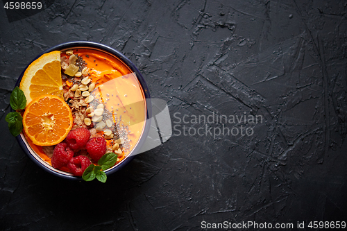 Image of Bowl with fresh healthy smoothie or yogurt. With orange slices, tangerine, raspberry, chia and nuts