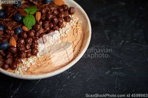 Image of Chocolate and blueberry smoothie or yogurt. With cocoa cornflakes, granola, mint leaves and almonds