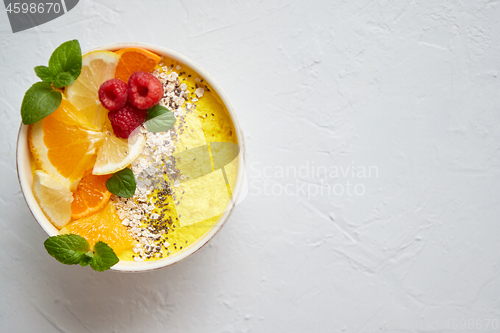 Image of Tasty orange fresh smoothie or yogurt served in bowl. With raspberries, orange slices, chia seeds