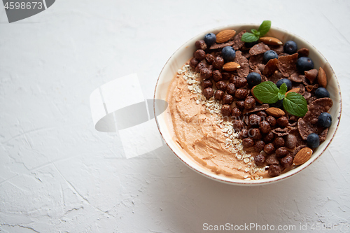 Image of Chocolate and blueberry smoothie or yogurt. With cocoa cornflakes, granola, mint leaves and almonds