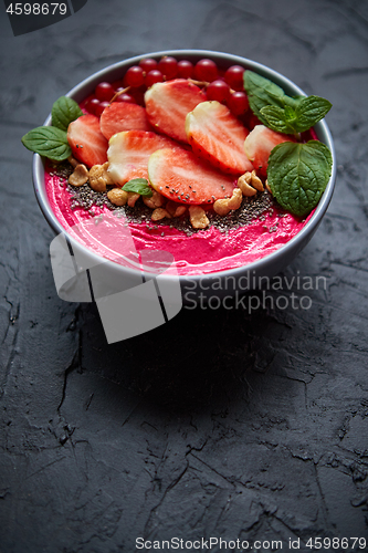 Image of Summer berry smoothie or yogurt bowl with strawberries, red currants and chia seeds on black