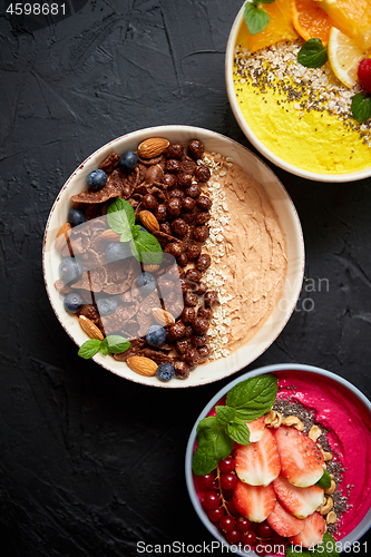 Image of Various healthy fresh smoothies or yogurts in bowls. With strawberries, kiwi, chia, blackberries