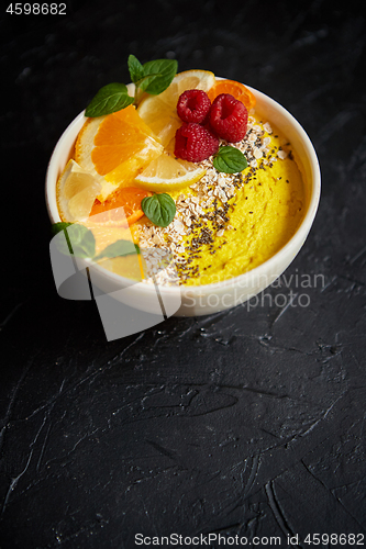 Image of Tasty orange fresh smoothie or yogurt served in bowl. With raspberries, orange slices, chia seeds