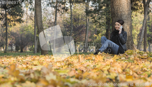 Image of Woman with a Mobile in a Forest in the Autumn