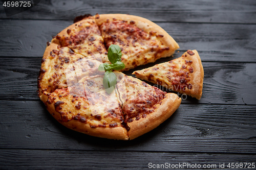 Image of Sliced pizza Margarita with basil leafs