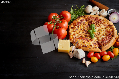Image of Delicious italian pizza served on black wooden table