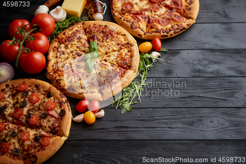 Image of Freshly served, three various pizzas placed among tasty ingredie