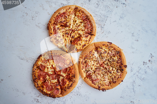 Image of Three american style pizzas served on a table