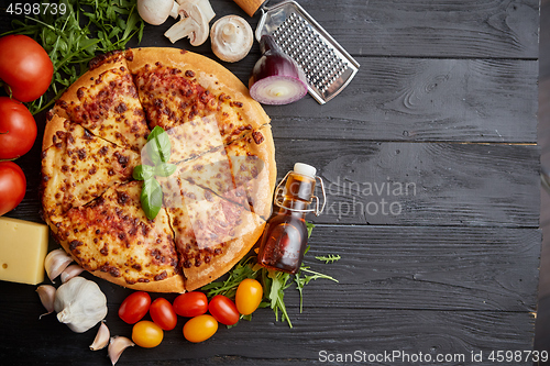 Image of Fresh baked, hot american style pizza with all various ingredients on side