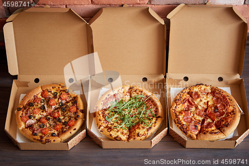 Image of Three different kind of pizzas in delivery boxes