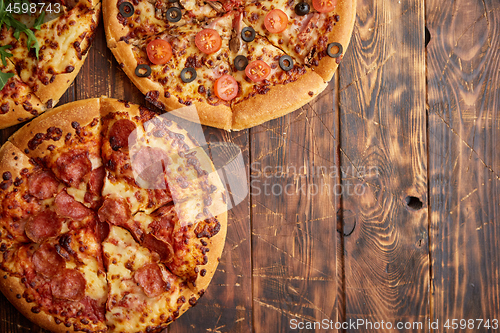 Image of Composition of three various kinds pizzas on wooden table