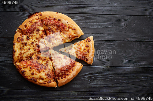 Image of Fluffy pepperoni pizza in american style placed on rusty old black wooden table