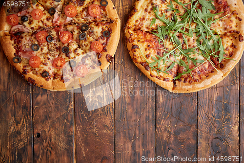 Image of Composition of two various kinds pizzas on wooden table