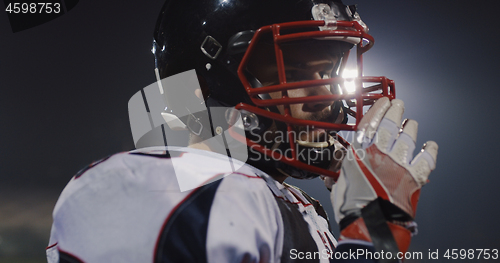 Image of American Football Player Putting On Helmet on large stadium with
