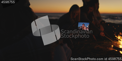 Image of Couple taking photos beside campfire on beach