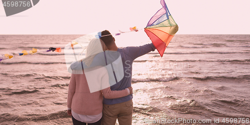 Image of Happy couple having fun with kite on beach