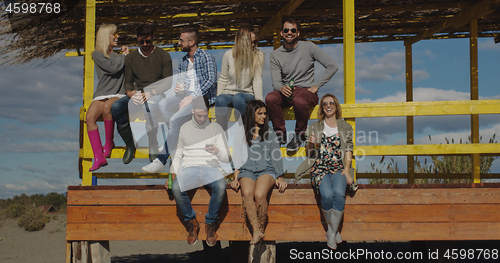 Image of Group of friends having fun on autumn day at beach